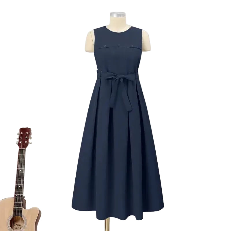 Navy blue dress on a mannequin against a white paneled wall with a guitar and small table with flowers in the background.